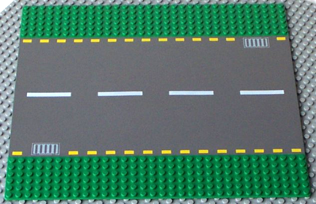 Display of LEGO part no. 44336pb01 which is a Green Baseplate, Road 32 x 32 6-Stud Straight with Dark Gray Road, Yellow Dashed Lines, and Light Gray Storm Drains Pattern 