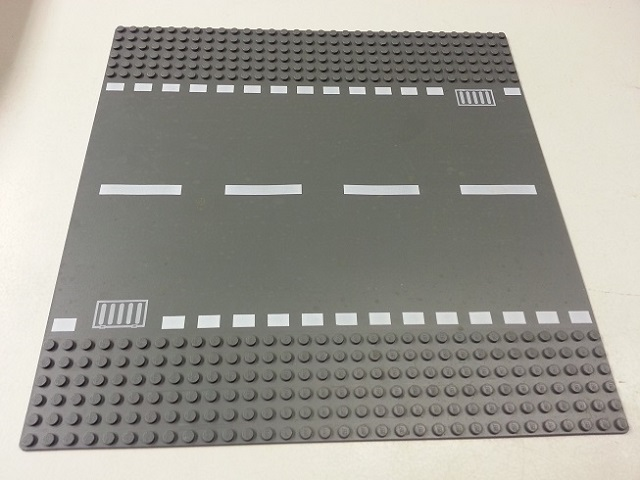 Display of LEGO part no. 44336px4 which is a Dark Bluish Gray Baseplate, Road 32 x 32 6-Stud Straight with White Dashed Lines and Storm Drain Pattern 