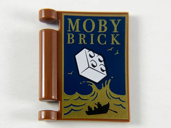 Display of LEGO part no. 24093pb026 Minifigure, Utensil Book Cover with Gold Ocean and 'MOBY BRICK', White Brick, Black Rowboat Pattern  which is a Reddish Brown Minifigure, Utensil Book Cover with Gold Ocean and 'MOBY BRICK', White Brick, Black Rowboat Pattern 