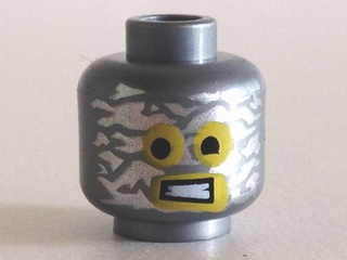Display of LEGO part no. 3626cpb1113 which is a Flat Silver Minifigure, Head Alien with Robot Yellow Eyes and Mouth and Aluminum Foil Splotches Pattern, Hollow Stud 