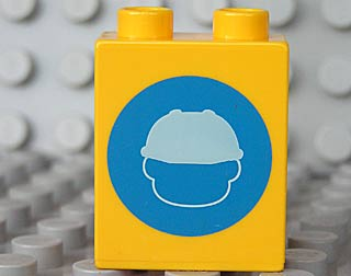 Display of LEGO part no. 4066pb317 Duplo, Brick 1 x 2 x 2 with Head in Construction Helmet on Blue Circle Pattern  which is a Yellow Duplo, Brick 1 x 2 x 2 with Head in Construction Helmet on Blue Circle Pattern 
