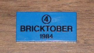 Display of LEGO part no. 87079pb0013 Tile 2 x 4 with Black '4' in Circle and 'BRICKTOBER 1984' Pattern  which is a Blue Tile 2 x 4 with Black '4' in Circle and 'BRICKTOBER 1984' Pattern 