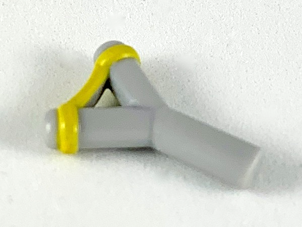 Display of LEGO part no. bb0664pb02 Minifigure, Weapon Slingshot with Yellow Band Pattern  which is a Light Bluish Gray Minifigure, Weapon Slingshot with Yellow Band Pattern 